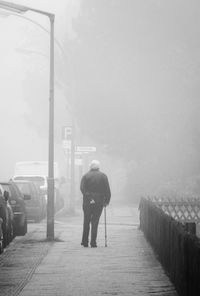 Rear view of man standing on railing against sky