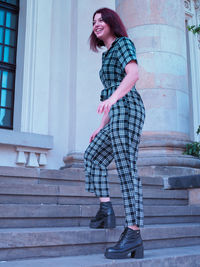 Portrait of woman standing against staircase