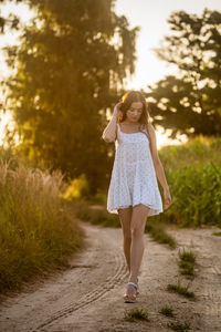 Young beautiful woman in white dress in corn field.