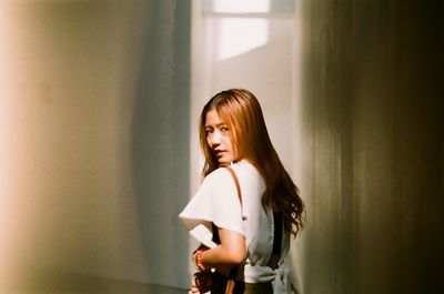 Rear view portrait of young woman in corridor