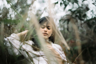 Low angle view of beautiful young woman standing amidst plants