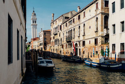 Boats moored in grand canal amidst old buildings against clear sky