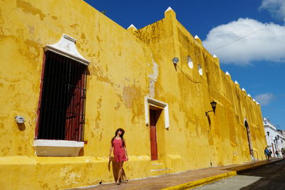 Full length of woman standing against yellow building