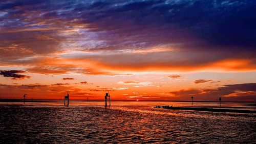 Scenic view of beach against dramatic sky during sunset