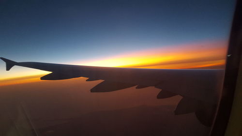 Close-up of airplane wing against sky during sunset