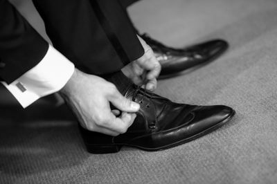 Low section of businessman tying shoelace on floor