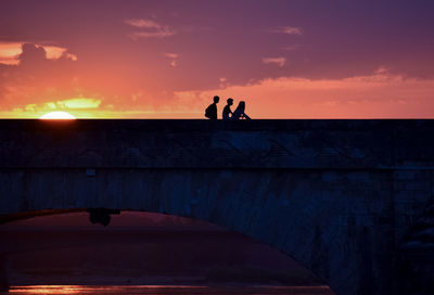 Silhouette people standing against orange sky