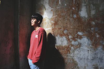 Full length of teenage boy standing against wall