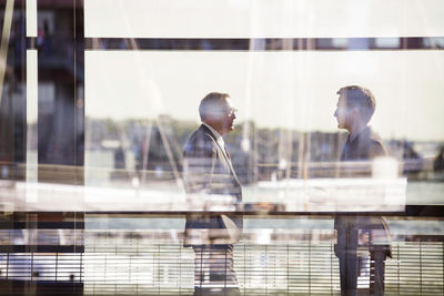 Businessmen standing against railing