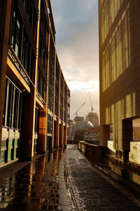 Street amidst buildings against sky during sunset