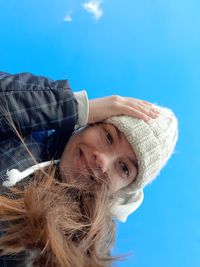 Portrait of young woman looking away against blue sky