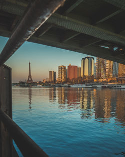 Buildings by river against sky in city