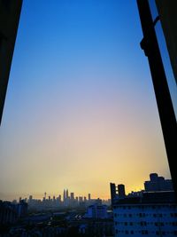 Buildings in city against clear sky during sunset