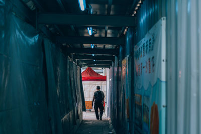 Rear view of man walking in tunnel