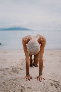 Rear view of woman with arms raised at beach