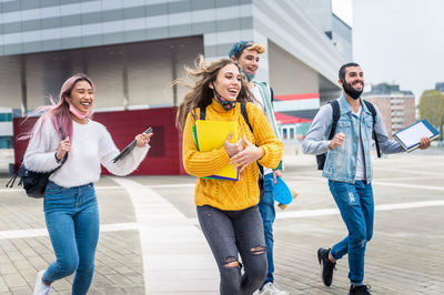 Cheerful friends carrying book outdoors