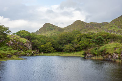 Scenic view of river by mountains against sky