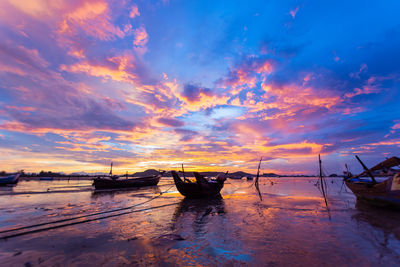 Boat moored on sea against sky during sunset