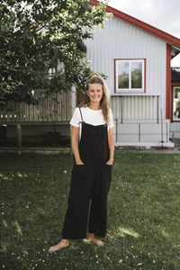 Mother with hands in pockets standing at back yard