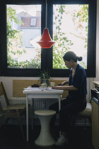 Full length side view of mature female architect using laptop at desk in home office