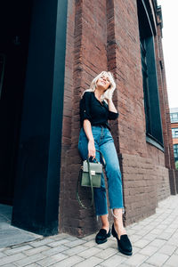 Full length of woman standing by building in city