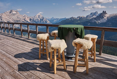 Chairs and tables on snow covered mountain against sky