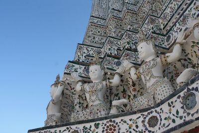 Low angle view of statues at wat arun against clear blue sky