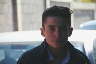 Close-up portrait of young man standing against car