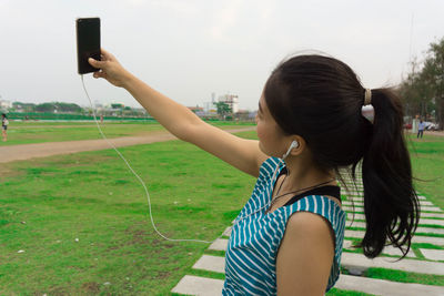 Side view of young woman using mobile phone in park