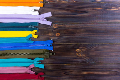 Multicolored zippers are laid out on a wooden table