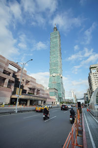 Vehicles on road amidst buildings in city against sky