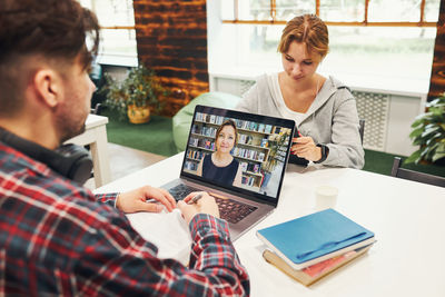 Young man using laptop while sitting on table