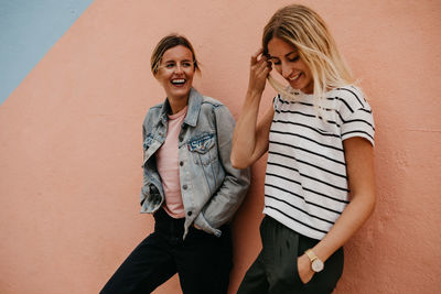 Happy woman standing against wall