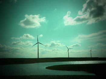 Wind turbines in sea against sky