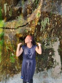 Woman standing on rock against wall