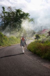 Man walking on road against sky