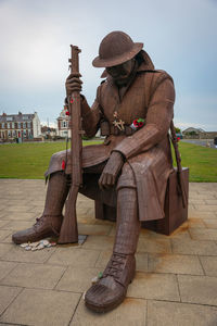 Midsection of man sitting on bench against sky