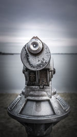 Close-up of metallic structure on beach against sky