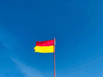 Low angle view of flag against clear blue sky