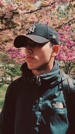 Portrait of young man wearing hat standing against plants