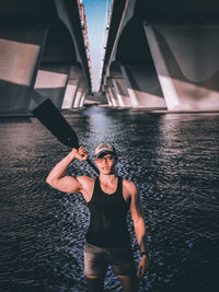 Portrait of young man standing against bridge