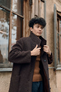 Portrait of young man standing against wall