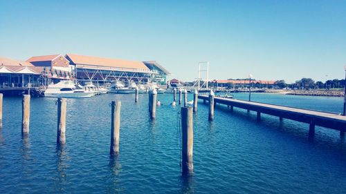 Pier in front of sea against clear blue sky