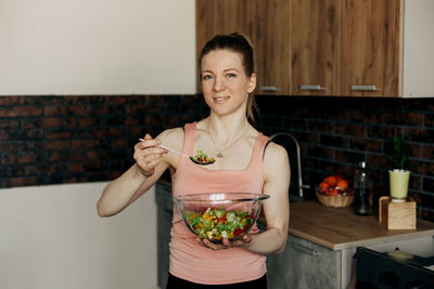 Portrait of an attractive woman holding a salad bowl and looking at the camera. beautiful athletic