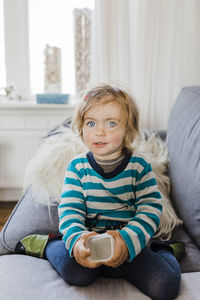 Portrait of cute girl sitting on sofa at home