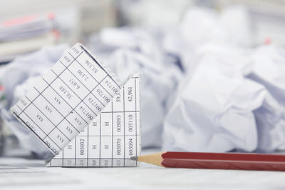 Close-up of crumpled paper balls with model house and pencil on financial documents