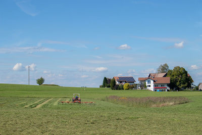 People on field by houses against sky