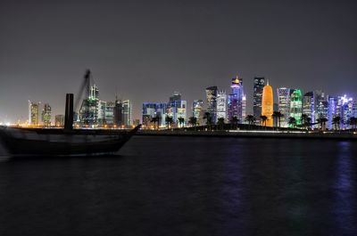 Illuminated modern buildings in city against sky at night