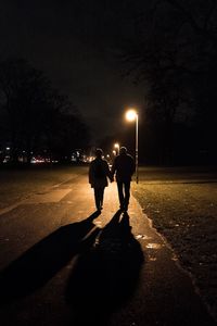 Rear view of silhouette people walking on road at night