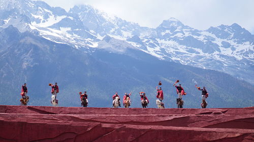 Group of people against snowcapped mountain 